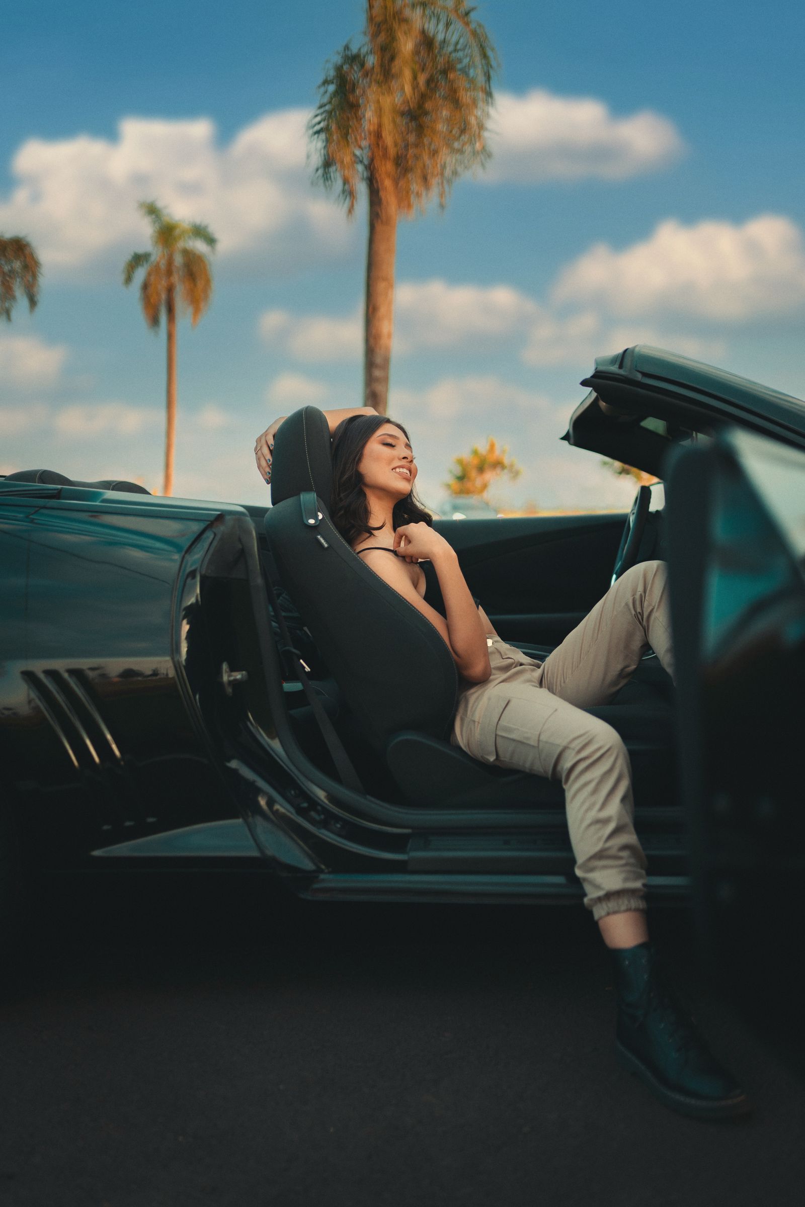 Woman relaxing in a convertible under palm trees on a sunny Miami day