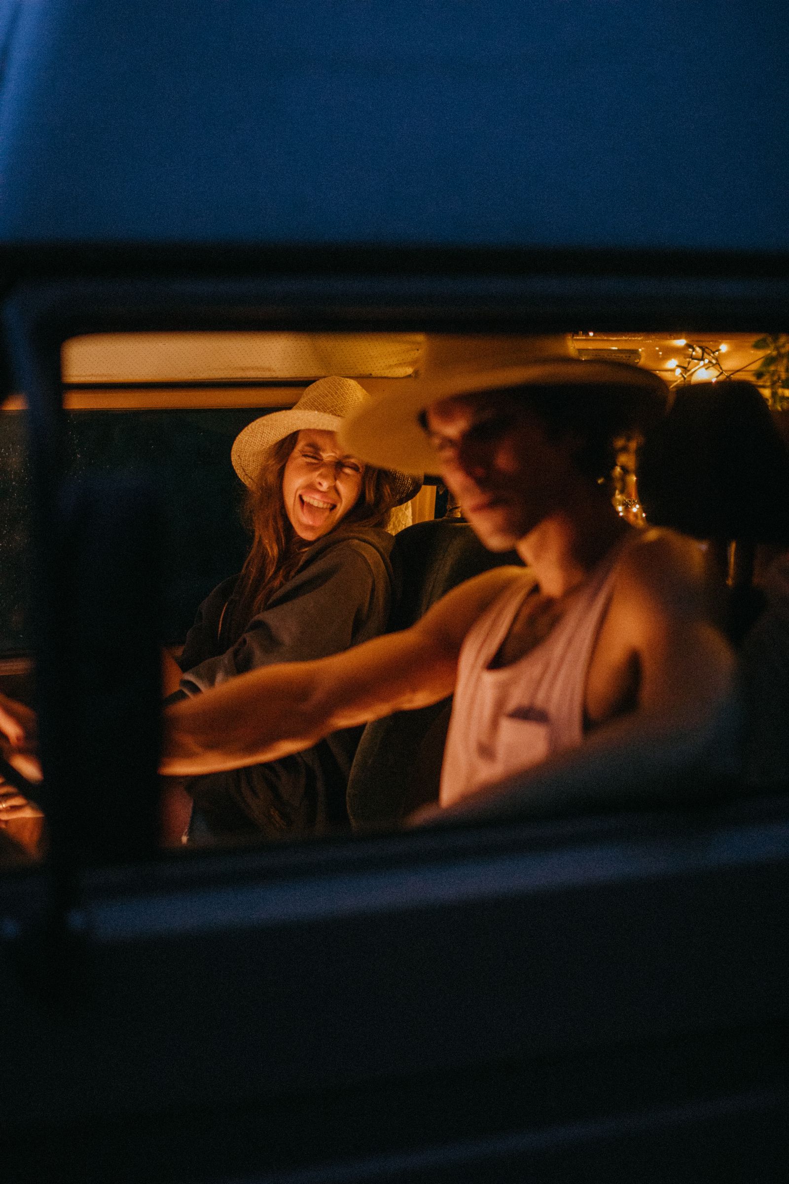 Young couple enjoying a playful road trip at night inside their van.